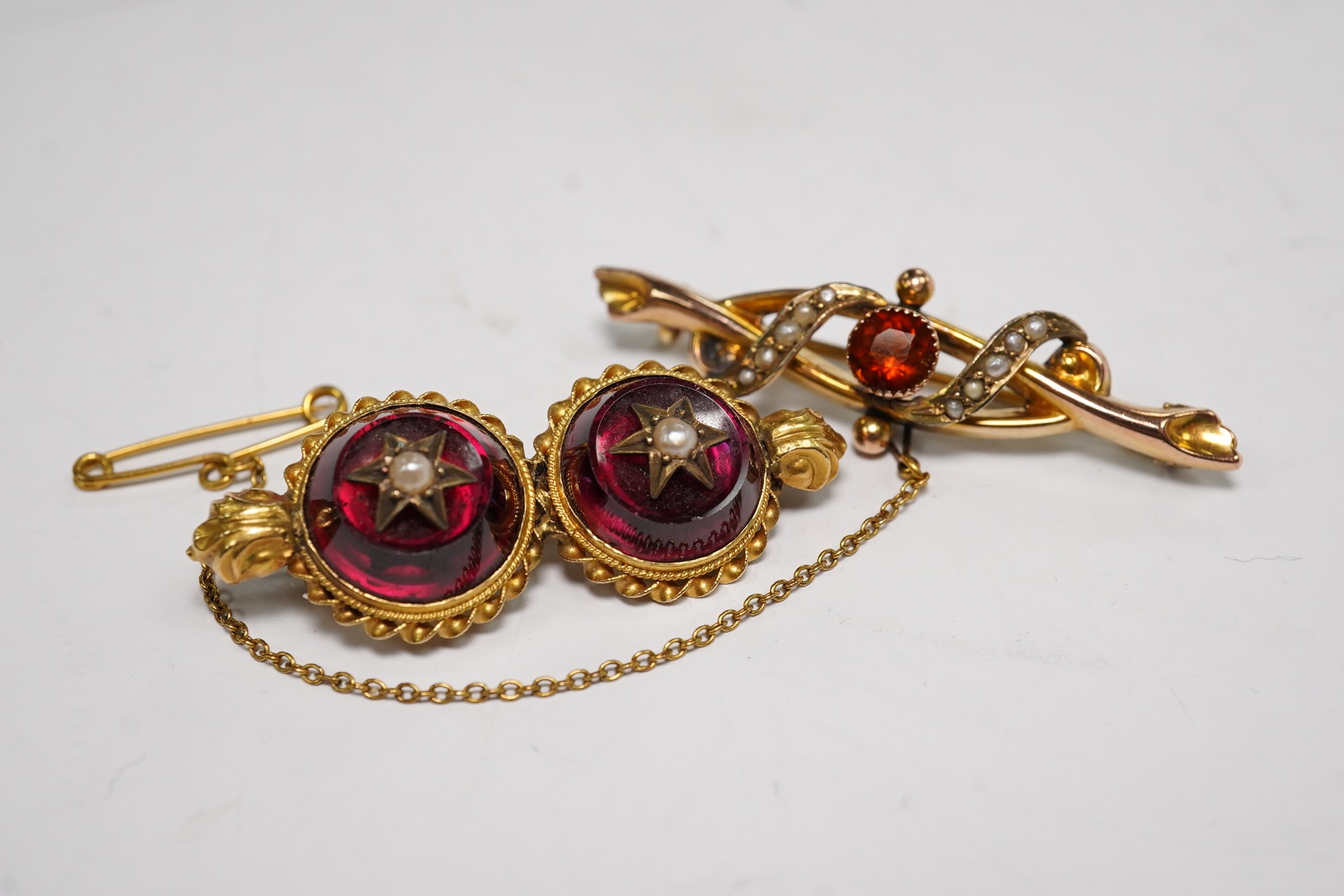 An Edwardian 9ct gold, hessonite garnet and seed pearl cluster set bar brooch, 42mm and a Victorian yellow metal, garnet and seed pearl set bar brooch, gross weight 7.3 grams, Condition - fair to good